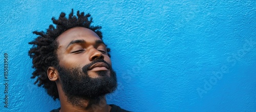 Man with beard and closed eyes against a vibrant blue abstract background with ample copy space for text or design elements