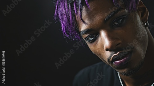 Close up portrait of African American male goth with purple hair and makeup on a dark background with space for billboard advertising text photo