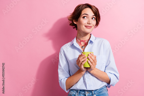 Portrait of pretty creative minded person hold coffee mug look empty space fantasize isolated on pink color background photo