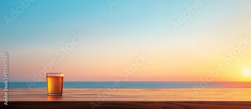 Scenic sunset view of a bar counter with a glass of drink overlooking the ocean under a clear blue sky with empty space for text