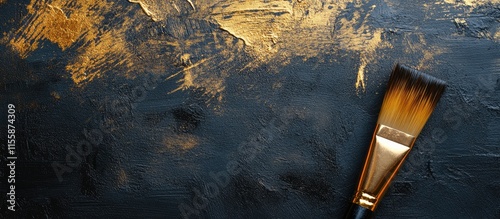 Close up of a paintbrush with gold paint on dark textured background for artistic and advertising use photo