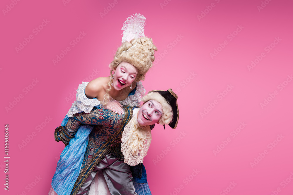 Fototapeta premium A couple dressed in elaborate vintage costumes poses against a vibrant pink background, embodying the elegance and glamour of a bygone era