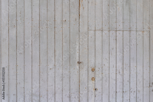 Deia, Mallorca, Spain 26.10.2021 Weathered white painted wooden door panel with vertical planks and rustic metal lock details.