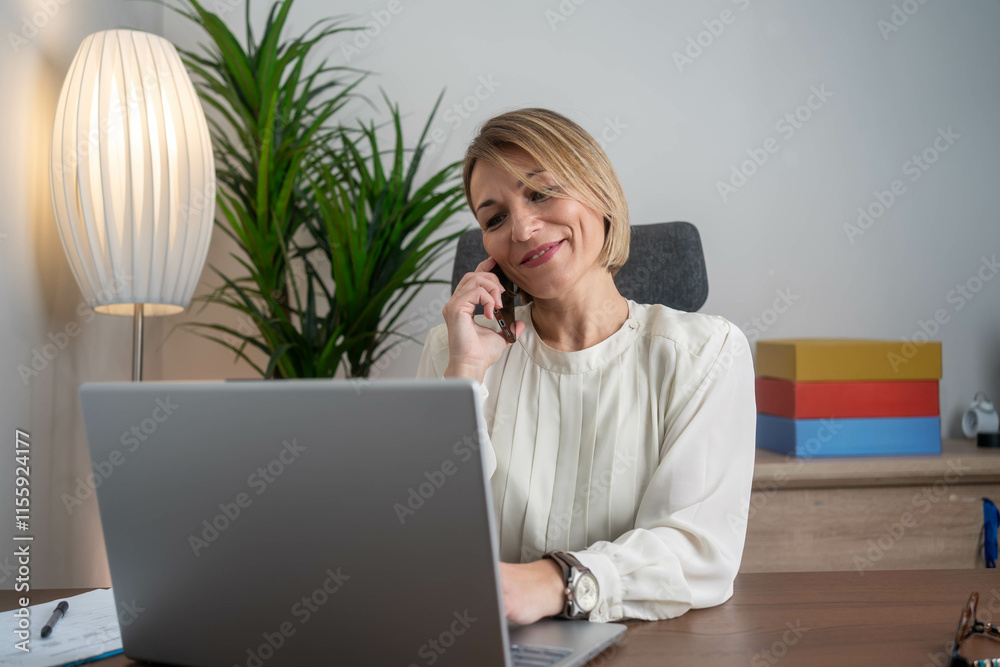 Portrait of mature smiling cheerful entrepreneur in casual office making phone call while working with laptop. Portrait of mature smiling cheerful entrepreneur in casual office making phone call while working with laptop.