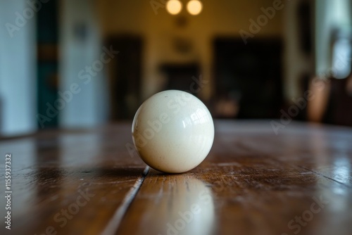 White spherical object resting on wooden surface with soft lighting and shado...