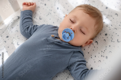 Cute baby with pacifier sleeping in crib at home