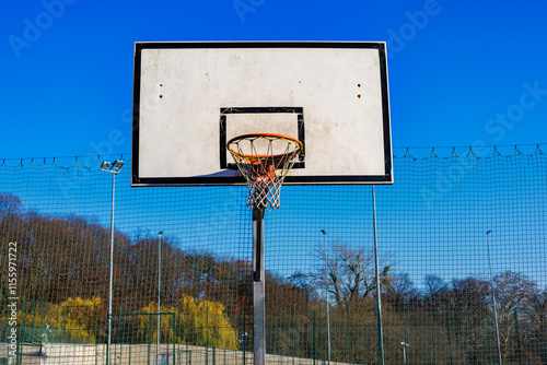 Basketball backboard with basket on fenced playground.