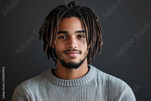 Portrait of young man with dreadlocks in gray sweater.