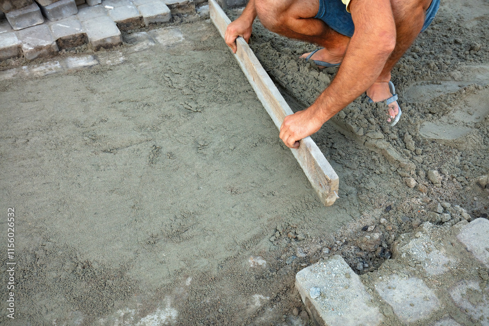 Handcrafted pavement takes shape under skilled hands in a sunny afternoon. Copy space.