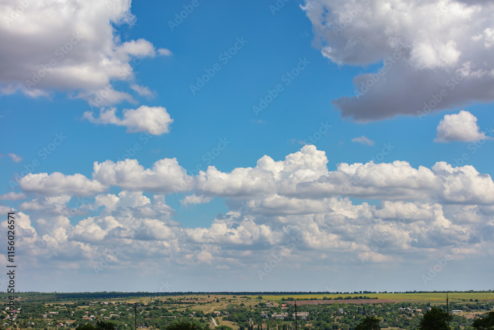 Majestic cotton candy clouds float lazily over a vast green landscape in bright daylight. Copy space.