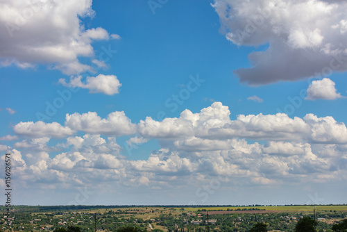 Obraz na płótnie Majestic cotton candy clouds float lazily over a vast green landscape in bright daylight. Copy space. w salonie
