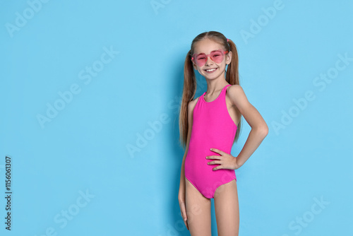 Fotografie Happy girl in beachwear on light blue background, space for text