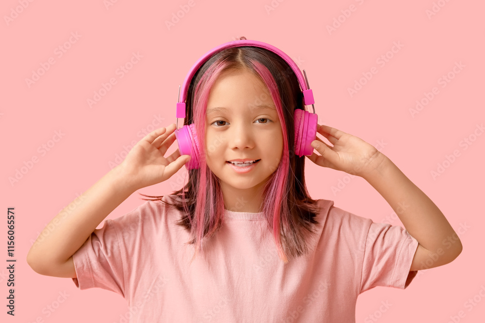 Cute little Asian girl in headphones on pink background Cute little Asian girl in headphones on pink background