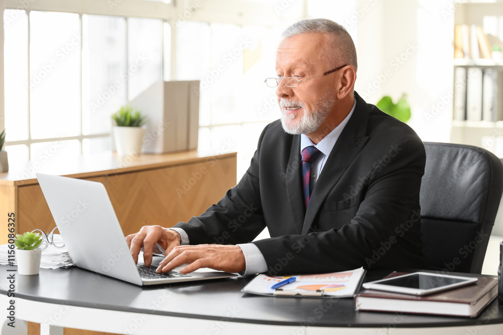 Senior businessman working with laptop at table in office Senior businessman working with laptop at table in office