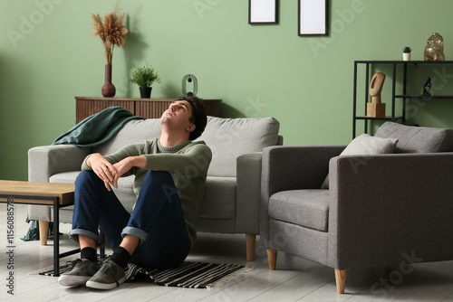 Depressed young man sitting on floor at home