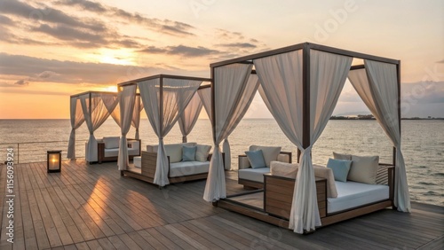Lounge beds nestled under elegant gazebos on a wooden deck invite relaxation as the sun sets over the calm ocean, creating a serene escape in a tropical resort