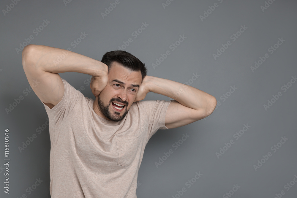 Man covering his ears on grey background, space for text Man covering his ears on grey background, space for text