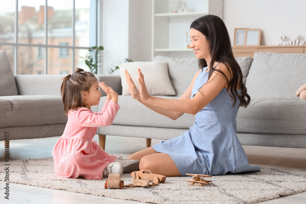 Φωτογραφία Young mother with her little daughter giving each other high-fives on carpet at