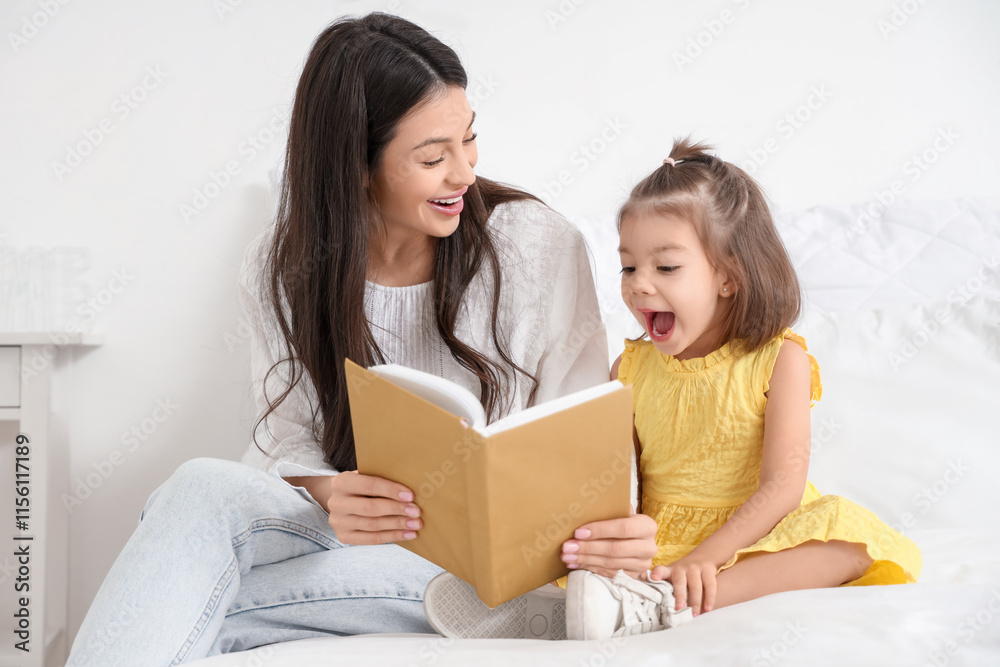 Young mother with her little daughter reading book in bedroom Young mother with her little daughter reading book in bedroom