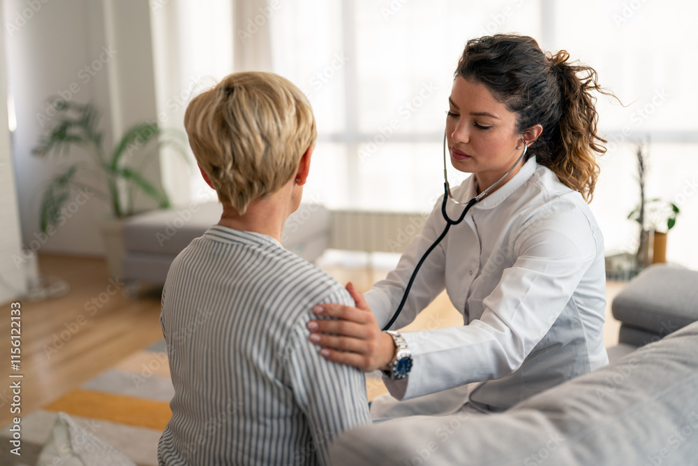 Obraz premium Female physician in white coat performs thorough medical examination using stethoscope during residential healthcare visit with senior patient in comfortable home environment.
