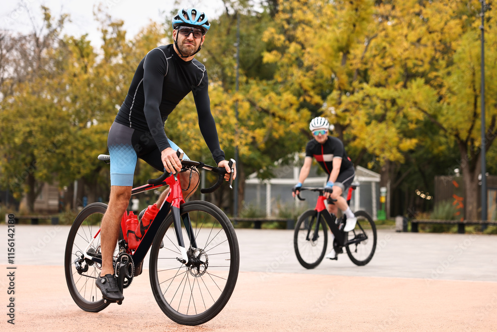 Fototapeta premium Athletic men with helmets riding bicycles outdoors