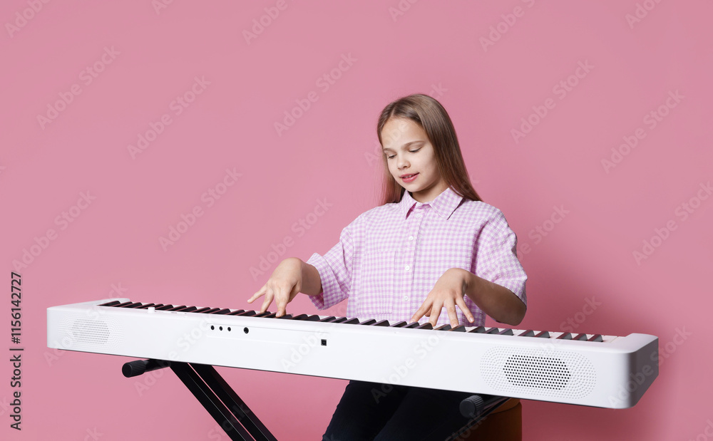 Cute girl playing synthesizer on pink background Cute girl playing synthesizer on pink background