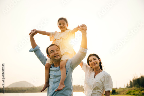 Asian family child girl piggyback riding back on father raising hands like flying outdoor nature park with mother, Happy parent daughter having fun together, Tourist lifestyle family leisure activity