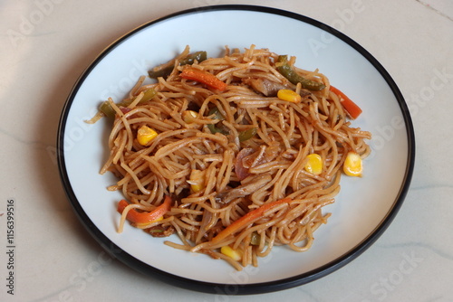 Chow mein or vegetable Hakka Noodles is a popular Indo-Chinese dish, served in plate, noodles stir fry with mushroom, sweet corn, vegetbales with sauce  photo