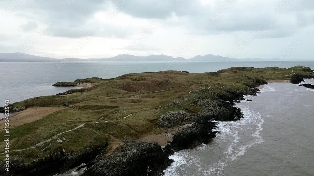 Aerial view establishing Ynys Llanddwyn island at rough tide with Snowdonia mountains on the horizon Aerial view establishing Ynys Llanddwyn island at rough tide with Snowdonia mountains on the horizon