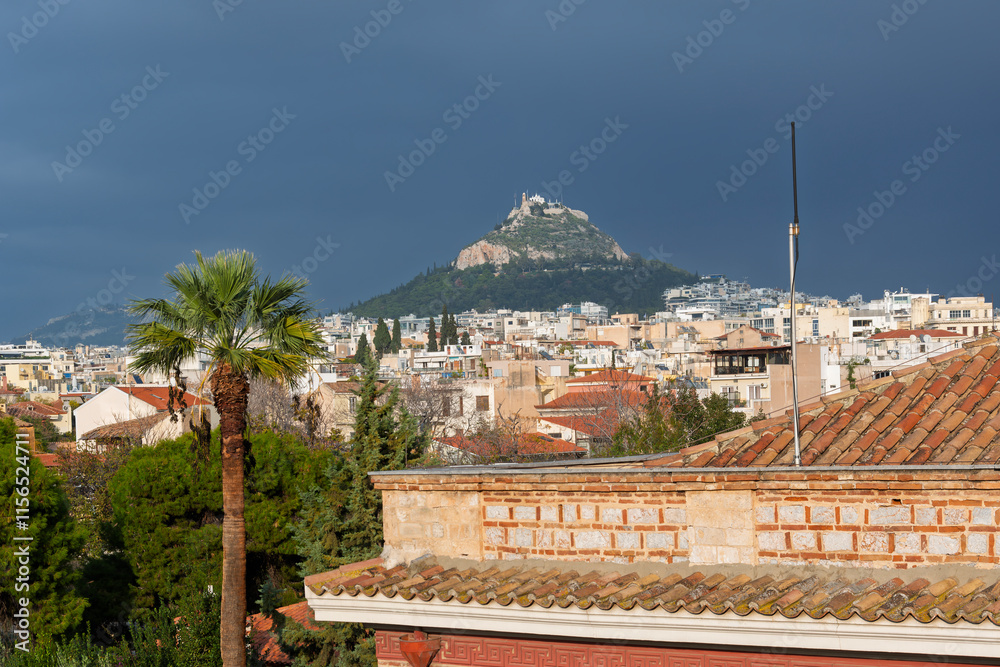 Obraz premium View of Mount Lycabettus and the historic downton of Athens, Greece, under dark stormy skies.