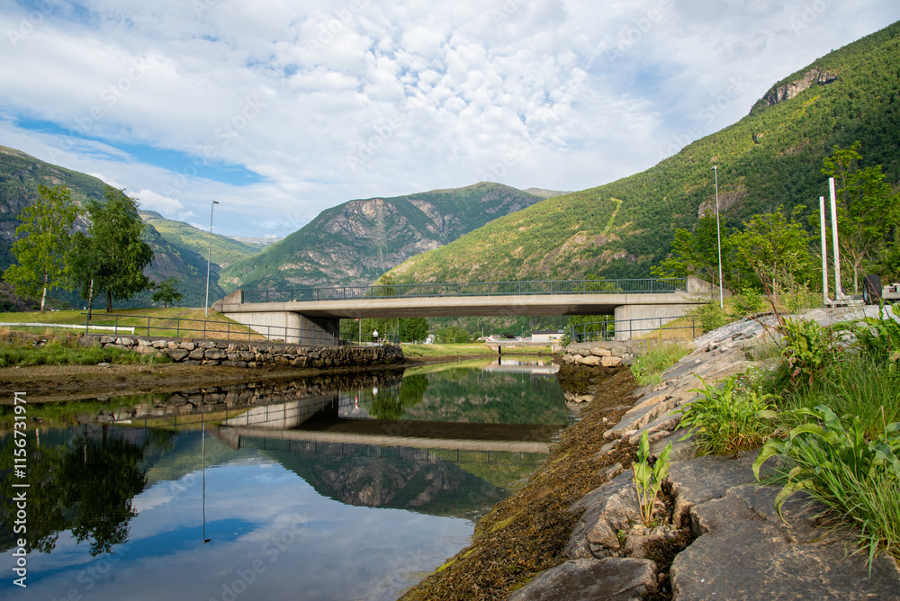 concrete bridge over a river with water like a mirror reflecting the beautiful Norwegian fjord mountains in the village of Lærdalsøyri. concrete bridge over a river with water like a mirror reflecting the beautiful Norwegian fjord mountains in the village of Lærdalsøyri.