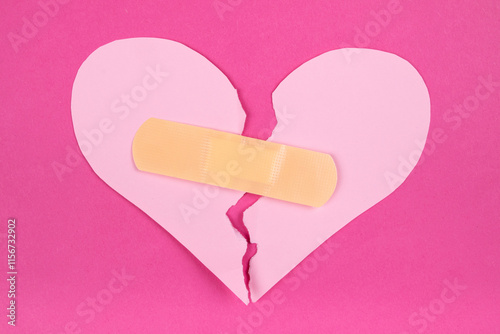 Torn paper pink heart with beige adhesive bandage. Healed broken heart concept