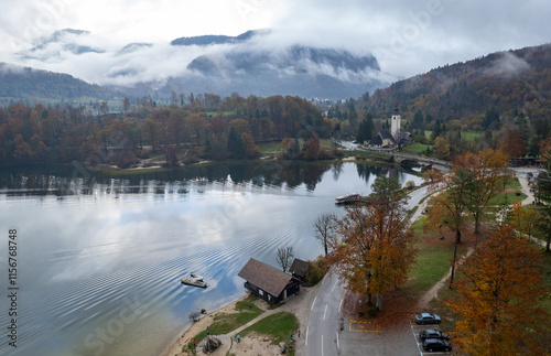 Motorboat sailing on bohinj lake near the church of st john the baptist on an autumn day photo