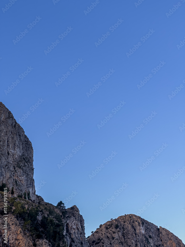 Naklejka premium Vertical image of rocky mountain on a blue sky in the background with copy space