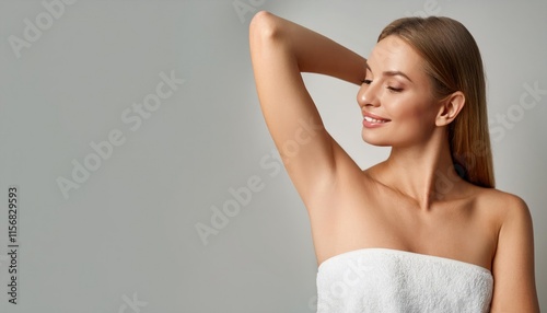 Young beautiful woman show smooth shaved armpits on grey color background with copy space. Laser epilation, electroepilation, removing unwanted hair permanently
