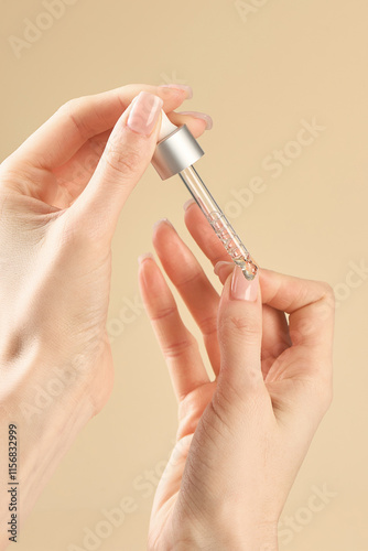 A woman applies nail care liquid to the skin with a pipette.