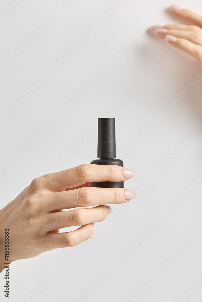 A woman's hands hold a bottle of nail polish A woman's hands hold a bottle of nail polish