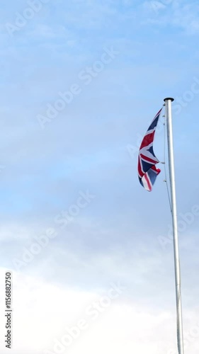 british flag waves wind against backdrop blue skies light clouds vibrant colors stand out clear atmosphere scene visuals heritage symbolism identity culture national pride  photo