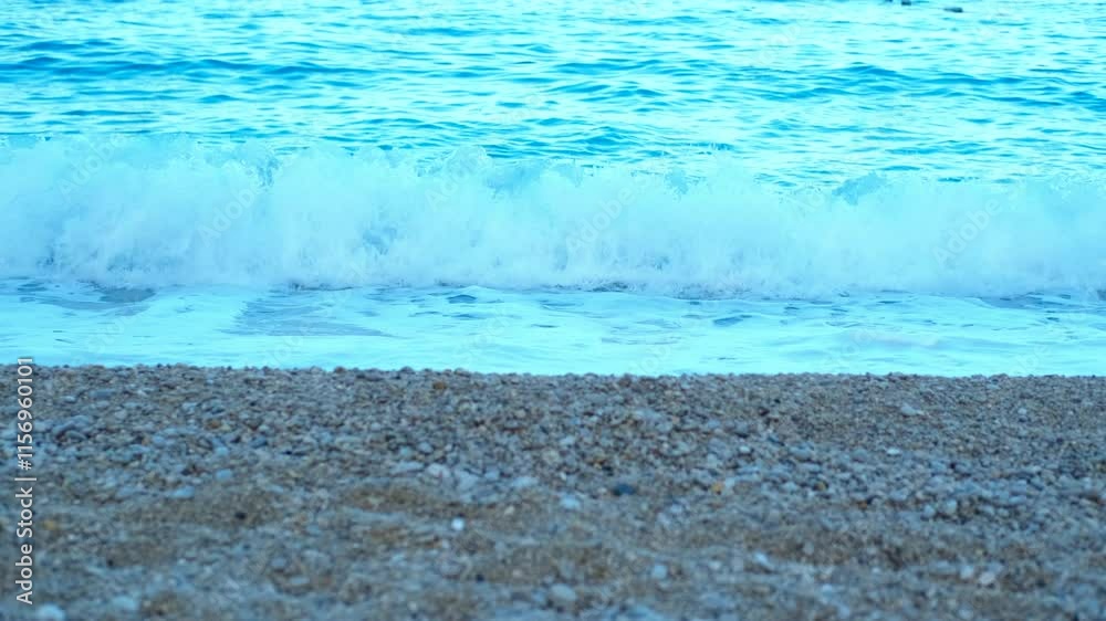 Blue waves on a pebble beach. Calm waters and a clear sky enhance the peaceful, idyllic setting, perfect for relaxation and tranquility Blue waves on a pebble beach. Calm waters and a clear sky enhance the peaceful, idyllic setting, perfect for relaxation and tranquility
