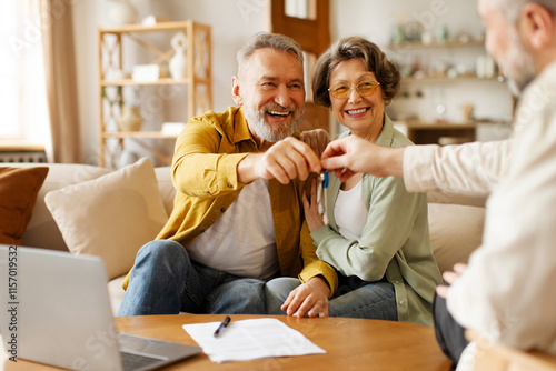 Real estate agent giving keys to excited senior couple buyers or clients, overjoyed loving spouses celebrating buy house