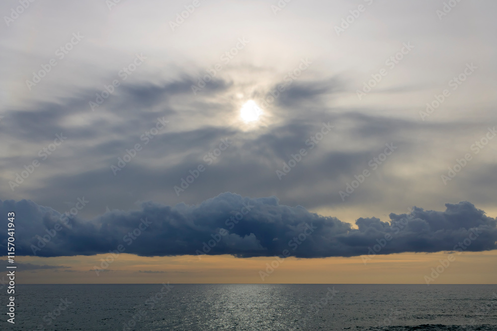 Fototapeta premium Dramatic sky above the sea glittering in pale sunlight