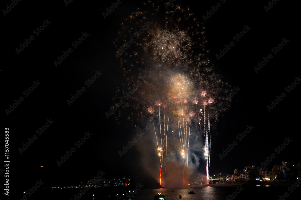 Colorful fireworks exploding over boats at night