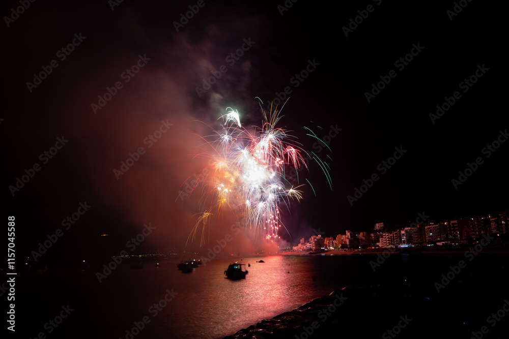 Colorful fireworks exploding over boats at night