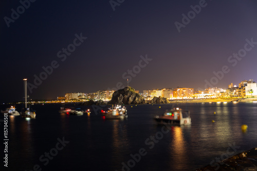 Obraz na płótnie People relaxing on beach at night, watching summer festival with illuminated buildings in background w salonie