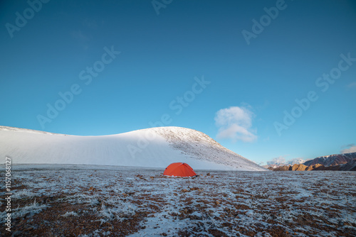 Wallpaper Mural Orange tent on snow-covered stony pass in sunlight. Snowy stone hill and rocky mountain ridge at early morning. Red tent in high mountains in freshly fallen snow. Low clouds in blue sky at sunrise. Torontodigital.ca