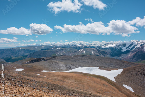 Wallpaper Mural Stony pass and snow-white glacier on rocky hill in sunlight among high mountains in sunny day. Large mountain range with snowy peaks in far away under clouds in blue sky. Most beautiful hilly terrain. Torontodigital.ca