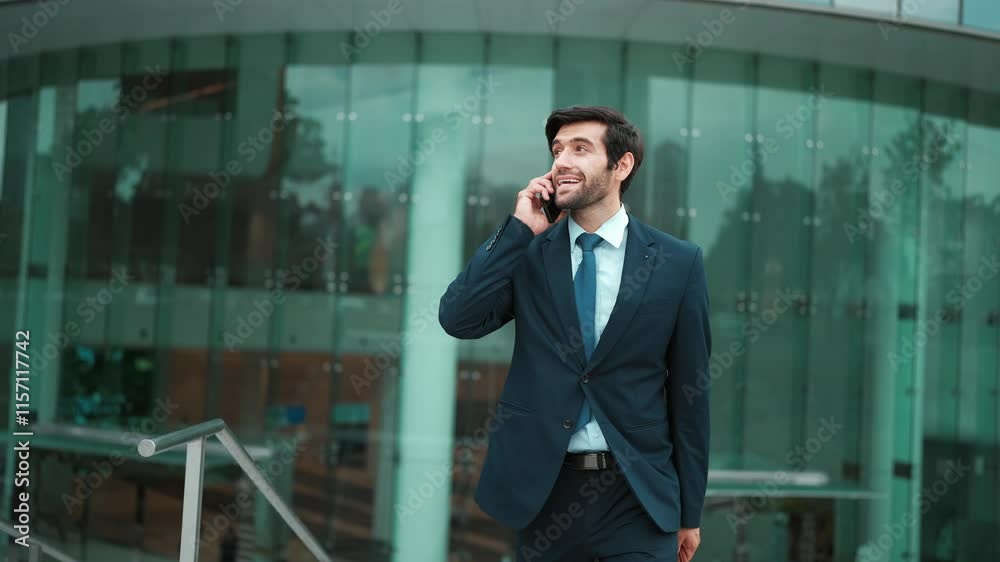 Skilled caucasian project manager calling phone while walking at city with blurred background. Skilled businessman using smart phone talking to project manager with blurred background. Exultant. Skilled caucasian project manager calling phone while walking at city with blurred background. Skilled businessman using smart phone talking to project manager with blurred background. Exultant.