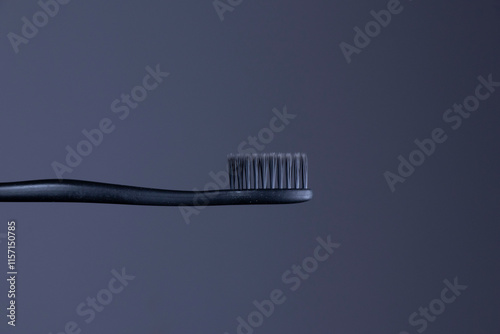 Black toothbrush with black bristles close-up on a gradient dark gray background