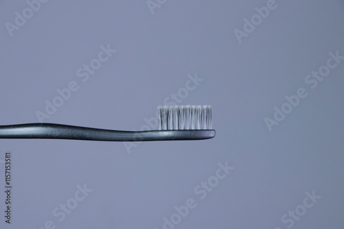 Gray toothbrush with gray bristles close-up on a gradient gray background