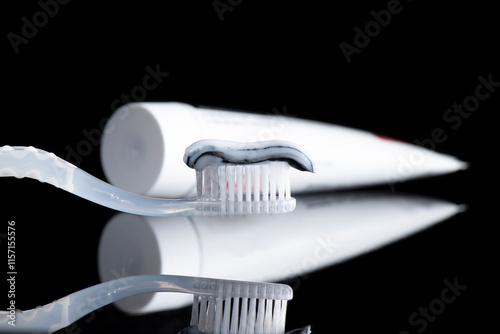 Toothpaste on a toothbrush close-up on a pure black background.
